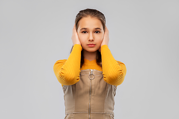 Image showing smiling teenage girl closing ears by hands