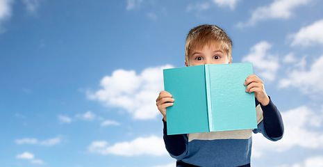 Image showing little boy hiding over book over sky