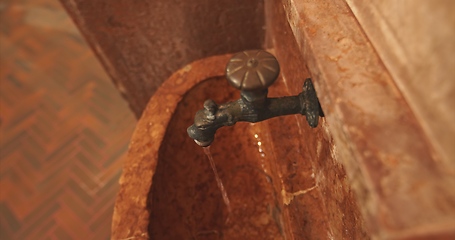 Image showing Old stone wash basin with decorative tap with water flowing