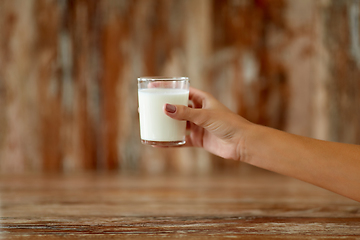 Image showing close up of female hand holding glass of milk