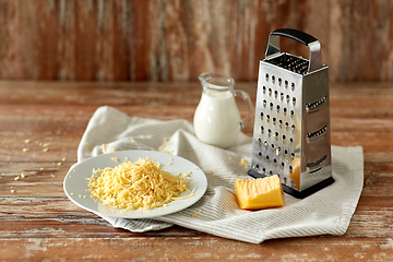 Image showing close up of grated cheese and jug of milk on table