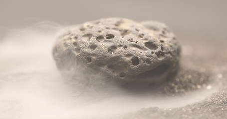 Image showing Smoke whirling around small meteorite stone