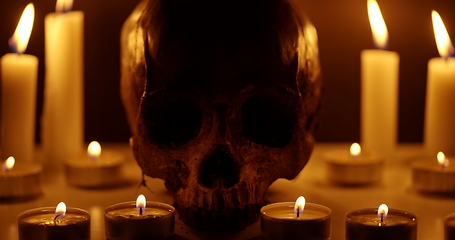 Image showing Candles and human skull in darkness closeup footage