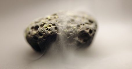 Image showing Smoke whirling around small meteorite stone