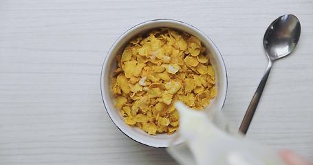 Image showing Pouring milk into bowl of cereals