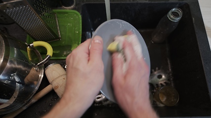 Image showing Washing dirty dishware in black sink