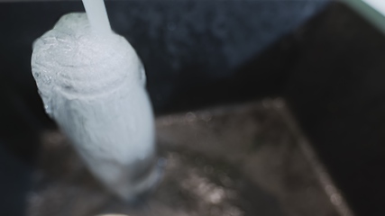 Image showing Clean water goes to waste while overfilling bottle