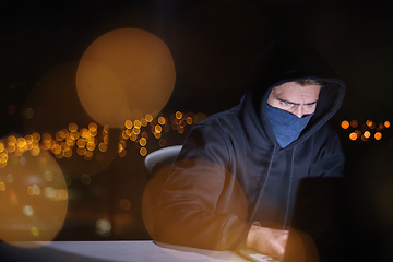 Image showing hacker using laptop computer while working in dark office