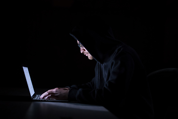 Image showing hacker using laptop computer while working in dark office