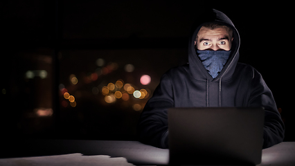 Image showing hacker using laptop computer while working in dark office