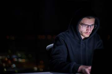 Image showing hacker using laptop computer while working in dark office