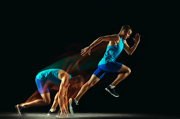 Image showing Professional male runner training isolated on black studio background in mixed light