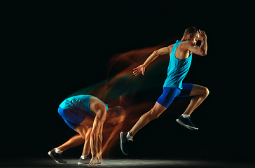 Image showing Professional male runner training isolated on black studio background in mixed light