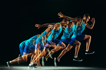 Image showing Professional male runner training isolated on black studio background in mixed light