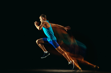 Image showing Professional male runner training isolated on black studio background in mixed light