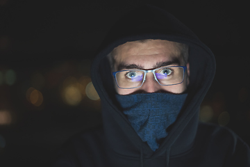 Image showing hacker using laptop computer while working in dark office