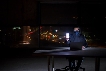 Image showing hacker using laptop computer while working in dark office