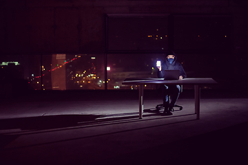 Image showing hacker using laptop computer while working in dark office