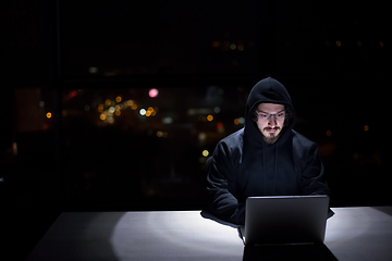 Image showing hacker using laptop computer while working in dark office