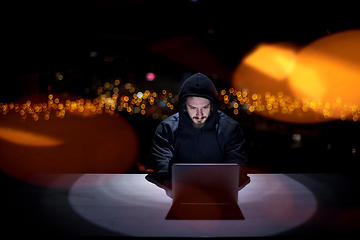 Image showing hacker using laptop computer while working in dark office