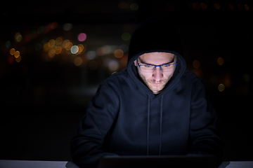 Image showing hacker using laptop computer while working in dark office