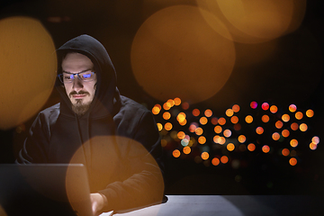 Image showing hacker using laptop computer while working in dark office