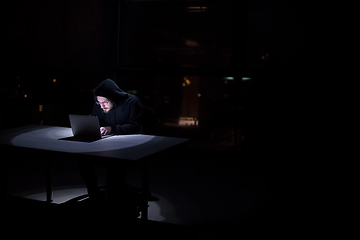 Image showing hacker using laptop computer while working in dark office