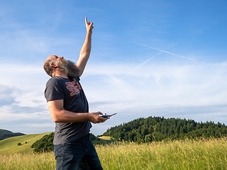 Image showing man pointing up to his drone in the sky