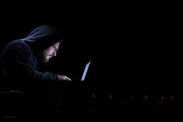 Image showing hacker using laptop computer while working in dark office