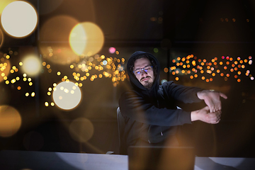 Image showing hacker using laptop computer while working in dark office