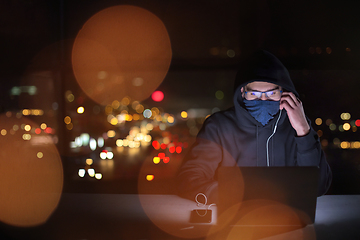 Image showing hacker using laptop computer while working in dark office