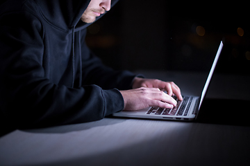 Image showing hacker using laptop computer while working in dark office