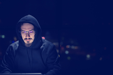 Image showing hacker using laptop computer while working in dark office