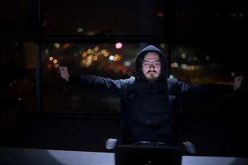 Image showing hacker using laptop computer while working in dark office