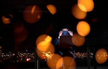 Image showing hacker using laptop computer while working in dark office