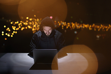 Image showing hacker using laptop computer while working in dark office