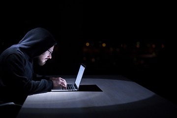 Image showing hacker using laptop computer while working in dark office