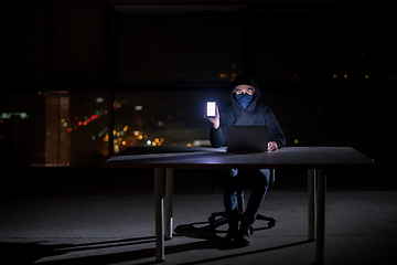 Image showing hacker using laptop computer while working in dark office