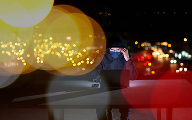 Image showing hacker using laptop computer while working in dark office