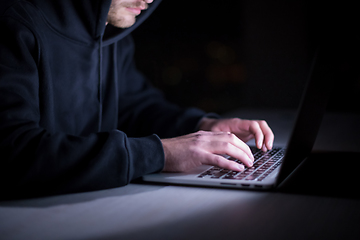 Image showing hacker using laptop computer while working in dark office