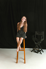 Image showing Young girl sitting on the high chair on black and white studio background