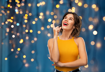 Image showing happy smiling young woman pointing finger up