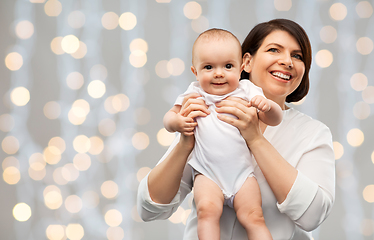 Image showing happy middle-aged mother with baby over lights