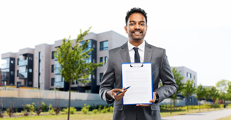 Image showing indian man realtor with contract on city street