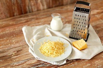 Image showing close up of grated cheese and jug of milk on table