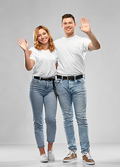 Image showing happy couple in white t-shirts waving hands