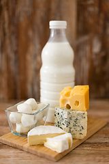 Image showing different kinds of cheese and milk on wooden board