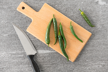 Image showing green chili peppers and knife on cutting board