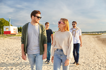 Image showing happy friends walking along summer beach