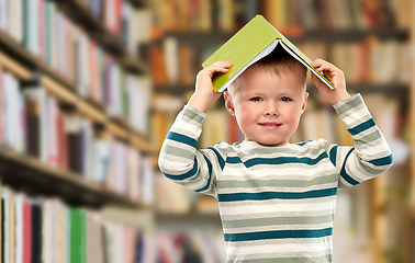 Image showing smiling boy with book on head over library